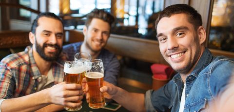 people, leisure, friendship, technology and bachelor party concept - happy male friends taking selfie and drinking beer at bar or pub